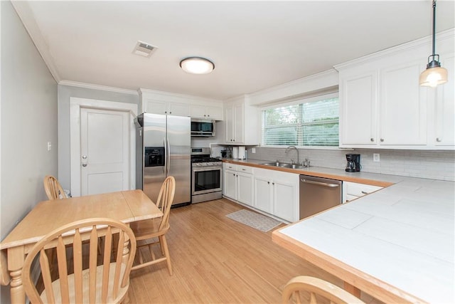 kitchen featuring hanging light fixtures, sink, tasteful backsplash, white cabinetry, and appliances with stainless steel finishes