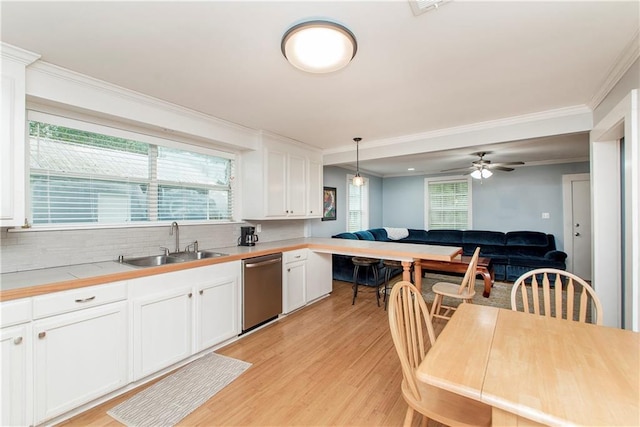 kitchen with light hardwood / wood-style floors, white cabinets, sink, stainless steel dishwasher, and decorative light fixtures