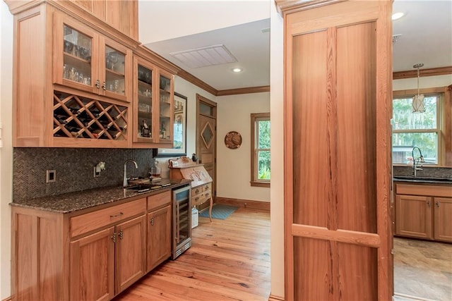 kitchen with beverage cooler, sink, a healthy amount of sunlight, and light hardwood / wood-style flooring