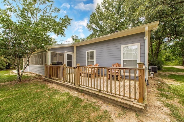 back of property with a sunroom, central AC, a lawn, and a wooden deck