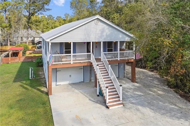 beach home with a front lawn, stairway, covered porch, concrete driveway, and an attached garage