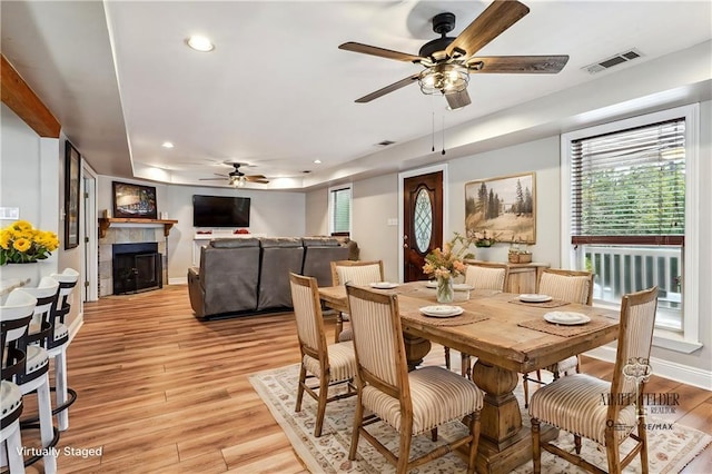 dining space featuring light wood-type flooring, visible vents, recessed lighting, a fireplace, and baseboards