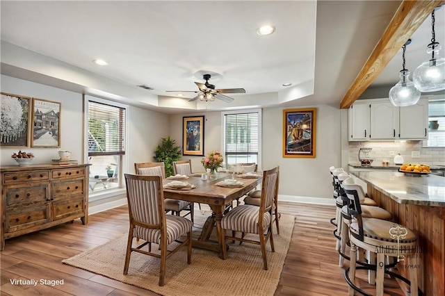 dining area featuring ceiling fan, light hardwood / wood-style floors, beam ceiling, and a wealth of natural light