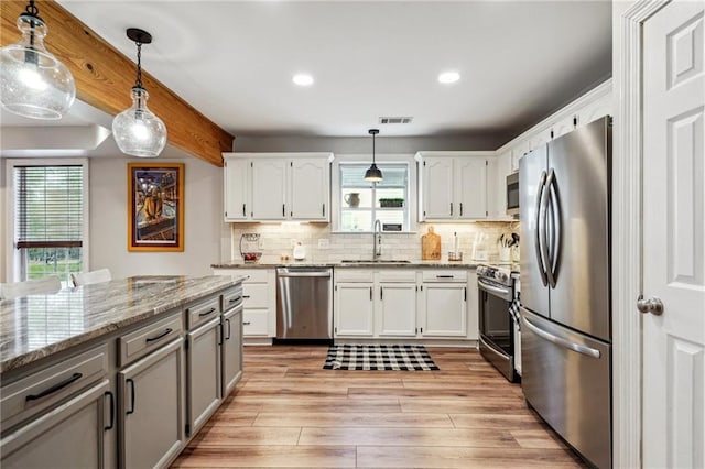 kitchen with visible vents, light wood-type flooring, decorative backsplash, appliances with stainless steel finishes, and a sink