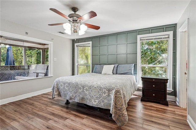 bedroom with baseboards, multiple windows, and wood finished floors