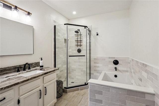 full bathroom featuring vanity, a garden tub, and a shower stall