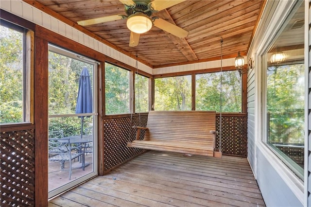 unfurnished sunroom featuring ceiling fan, a wealth of natural light, and wood ceiling