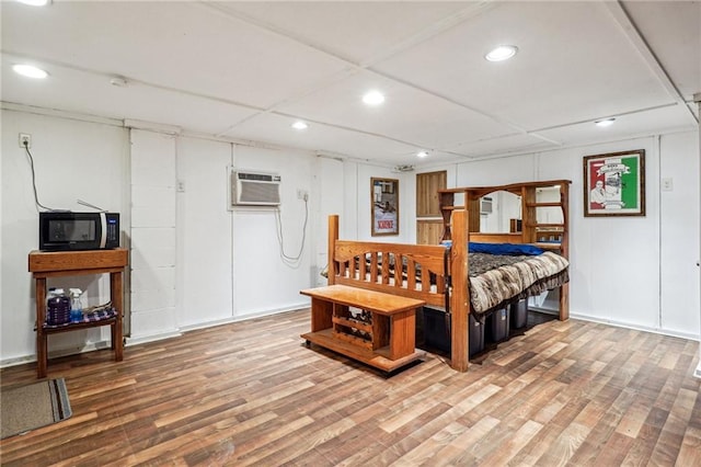 bedroom with recessed lighting, wood finished floors, and a wall unit AC