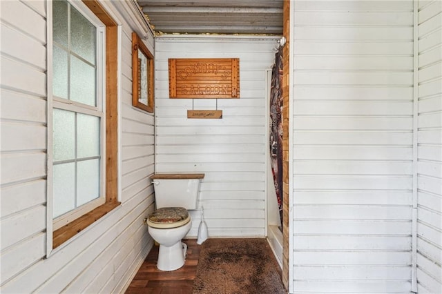 bathroom with hardwood / wood-style floors, wood walls, and toilet