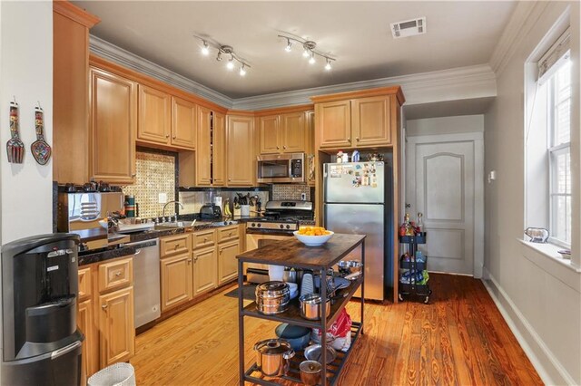 kitchen with light hardwood / wood-style floors, tasteful backsplash, appliances with stainless steel finishes, and ornamental molding