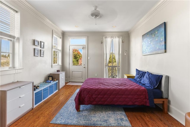 bedroom featuring multiple windows, hardwood / wood-style floors, ornamental molding, and ceiling fan