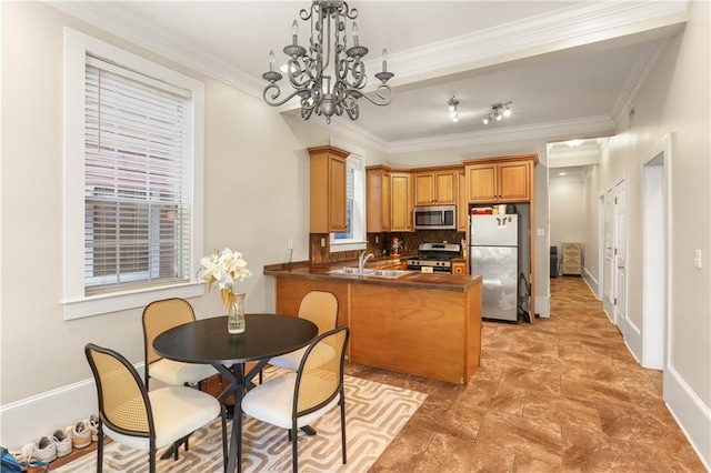 kitchen featuring kitchen peninsula, appliances with stainless steel finishes, an inviting chandelier, crown molding, and decorative backsplash