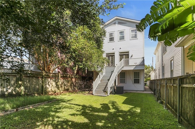 back of house featuring cooling unit, a lawn, and a wooden deck