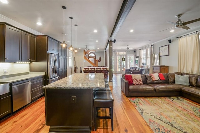 kitchen featuring a center island, appliances with stainless steel finishes, light hardwood / wood-style floors, and a breakfast bar area