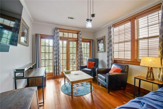 living area with hardwood / wood-style flooring, ornamental molding, and plenty of natural light