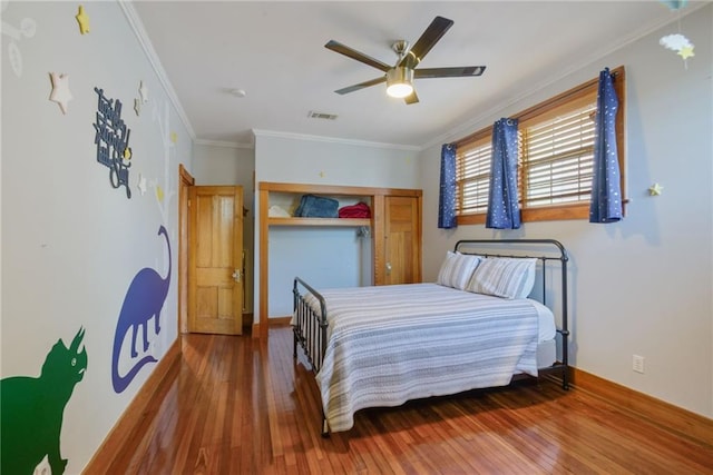 bedroom with ornamental molding, hardwood / wood-style floors, ceiling fan, and a closet