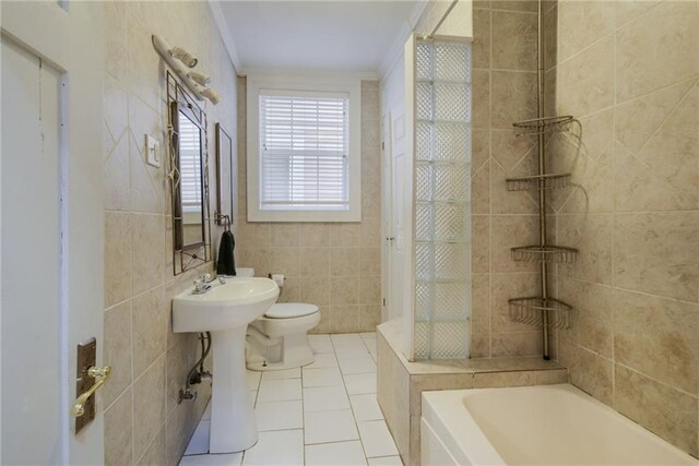 bathroom featuring toilet, tile patterned floors, tile walls, sink, and a tub to relax in