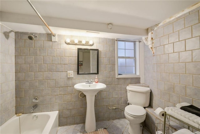 bathroom featuring tile walls, toilet, tiled shower / bath combo, and tile patterned floors