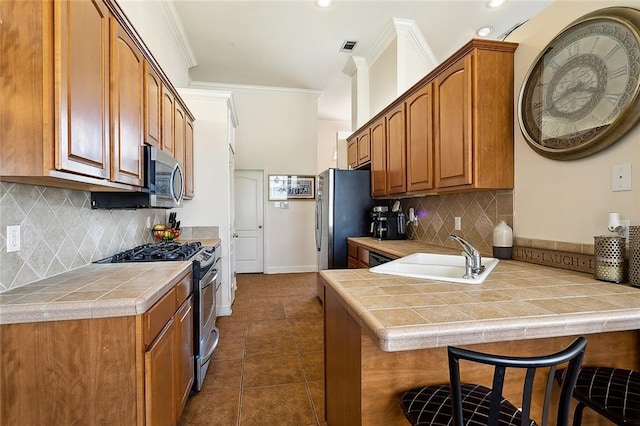 kitchen featuring tile countertops, decorative backsplash, kitchen peninsula, and appliances with stainless steel finishes