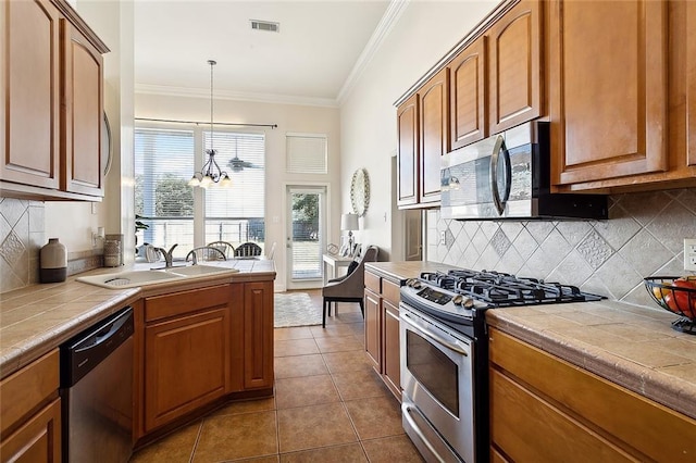 kitchen featuring tile countertops, dark tile patterned floors, a notable chandelier, and appliances with stainless steel finishes