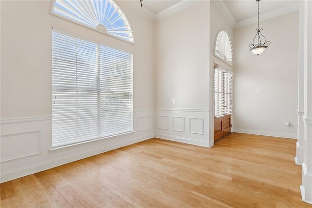 unfurnished room featuring plenty of natural light, ornamental molding, and light wood-type flooring