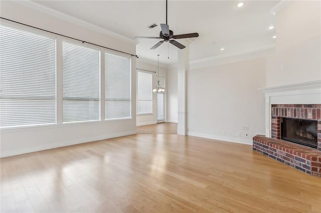 unfurnished living room featuring a brick fireplace, ceiling fan with notable chandelier, ornamental molding, and light hardwood / wood-style flooring