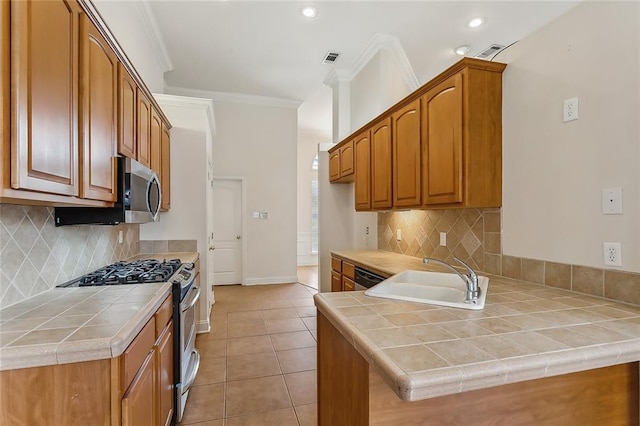 kitchen with kitchen peninsula, tile counters, appliances with stainless steel finishes, and sink