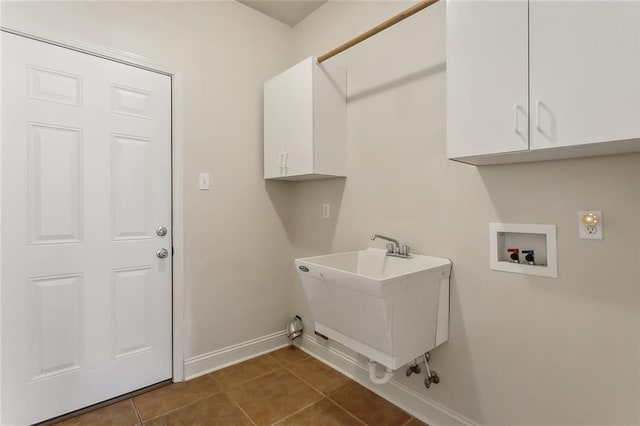 laundry room with dark tile patterned flooring, cabinets, sink, and hookup for a washing machine