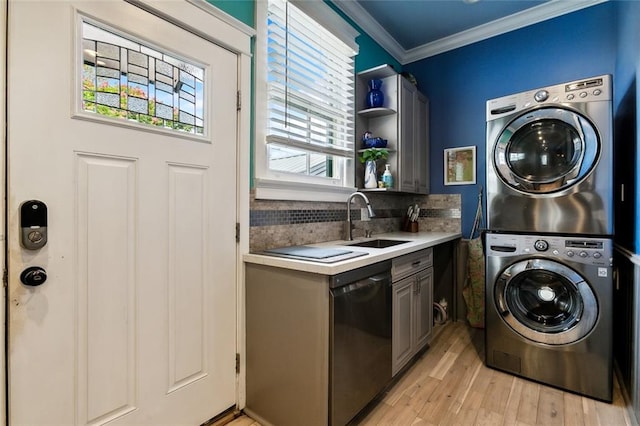 laundry room featuring cabinets, light hardwood / wood-style floors, stacked washer and clothes dryer, sink, and crown molding