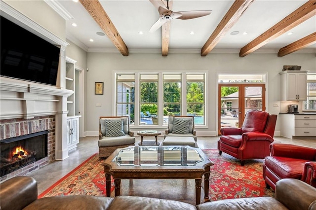 living room with a brick fireplace, beamed ceiling, ceiling fan, and crown molding