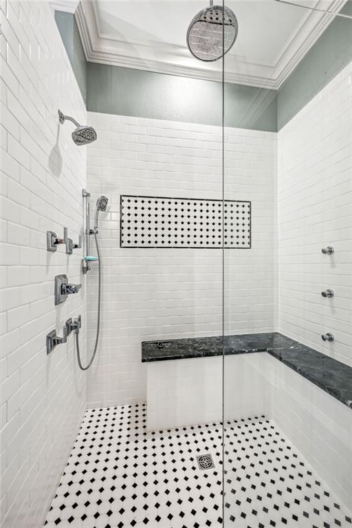 bathroom with tiled shower and crown molding