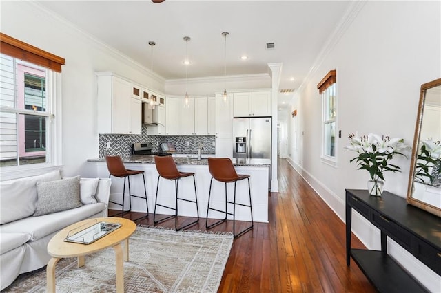 kitchen featuring stainless steel appliances, dark stone counters, white cabinetry, dark hardwood / wood-style floors, and hanging light fixtures