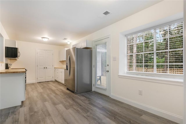 kitchen with stainless steel refrigerator with ice dispenser, white cabinetry, light wood-type flooring, and wooden counters