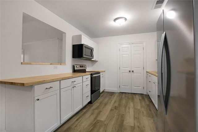 kitchen featuring wood counters, white cabinetry, light hardwood / wood-style flooring, and appliances with stainless steel finishes