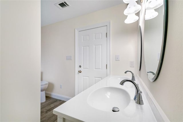 bathroom with hardwood / wood-style floors, vanity, and toilet