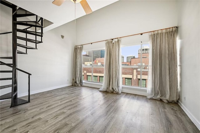 333 Julia St Unit 516, New Orleans, LA 70130 - unfurnished living room with wood finished floors, stairway, a ceiling fan, and a towering ceiling