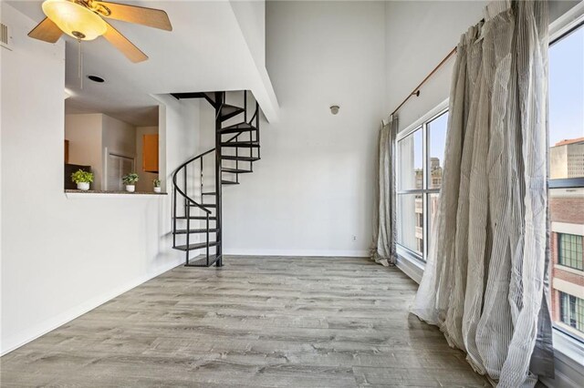 333 Julia St Unit 516, New Orleans, LA 70130 - empty room with wood finished floors, plenty of natural light, stairs, and ceiling fan
