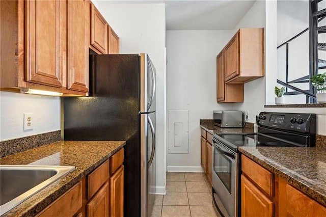 kitchen with dark stone counters, sink, light tile patterned flooring, and stainless steel appliances