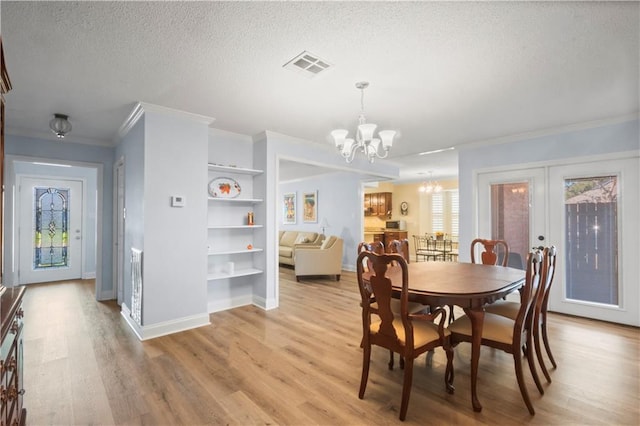 dining room with a notable chandelier, french doors, a textured ceiling, and light hardwood / wood-style flooring