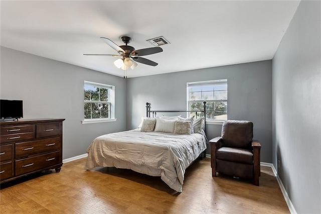 bedroom featuring ceiling fan, multiple windows, and light wood-type flooring