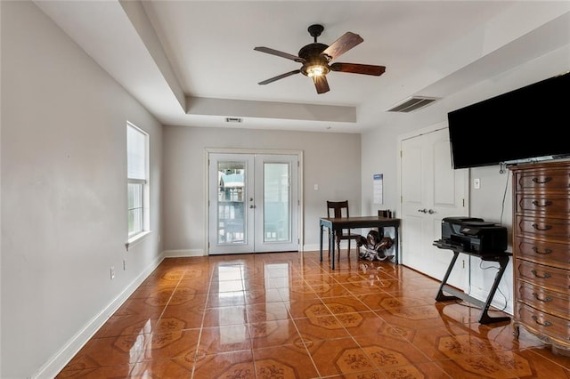 interior space with a tray ceiling, french doors, tile patterned flooring, and ceiling fan