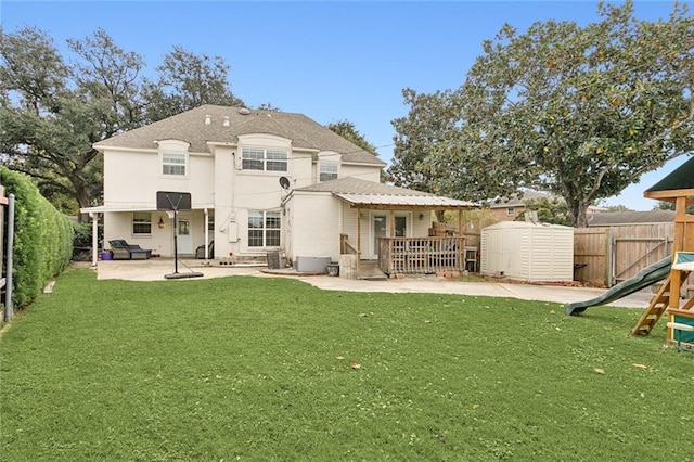 rear view of property featuring a yard, a patio, a storage shed, and a playground