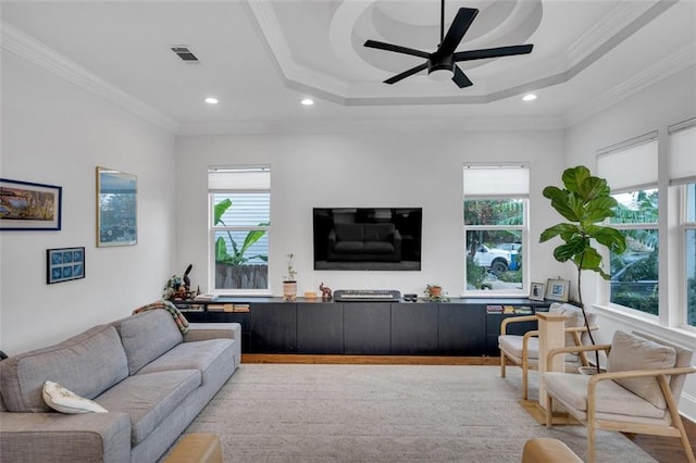 living room featuring ceiling fan, a raised ceiling, ornamental molding, and light hardwood / wood-style flooring