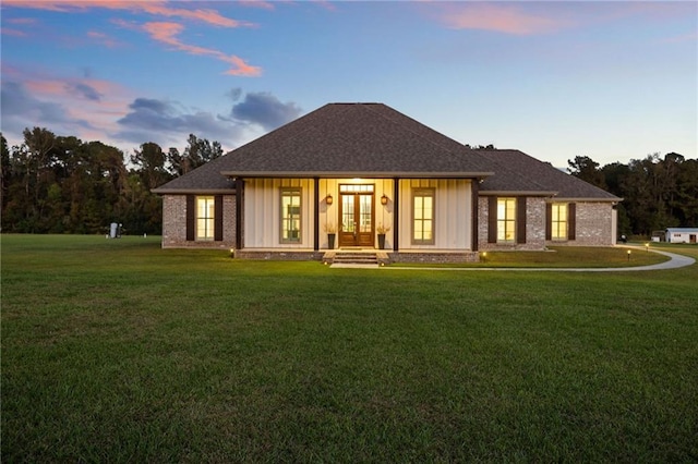 back house at dusk with a lawn and french doors