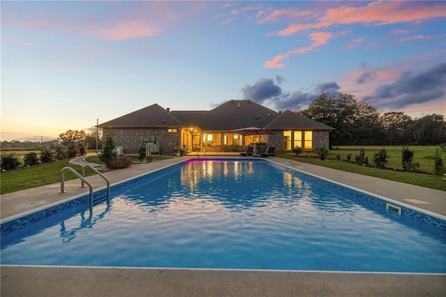 pool at dusk featuring a patio