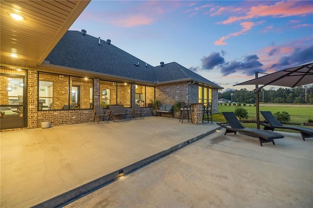 back house at dusk featuring a patio