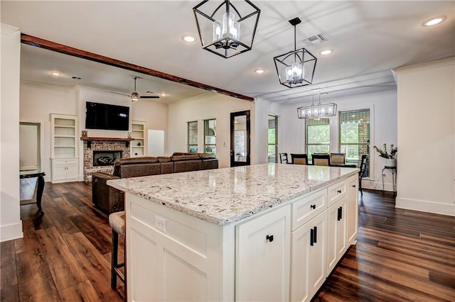 kitchen with white cabinets, a kitchen island, dark wood-type flooring, and pendant lighting