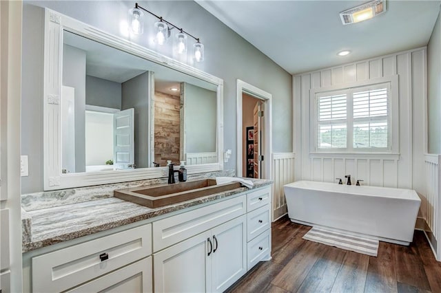 bathroom with a bathtub, vanity, and wood-type flooring