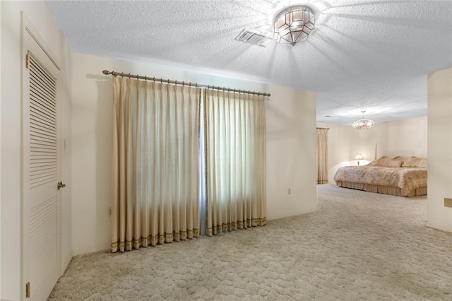 unfurnished bedroom with carpet floors, a chandelier, and a textured ceiling