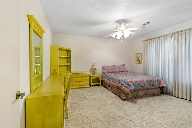 bedroom with ceiling fan, carpet floors, and a textured ceiling